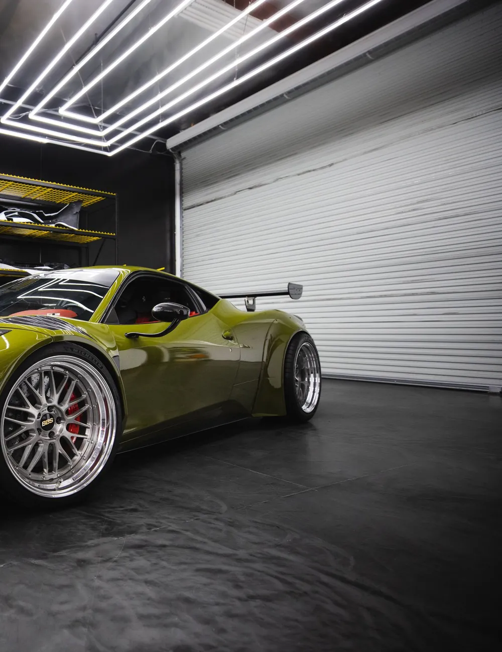 Showroom garage with a glossy dark metallic epoxy floor reflecting an overhead light rig